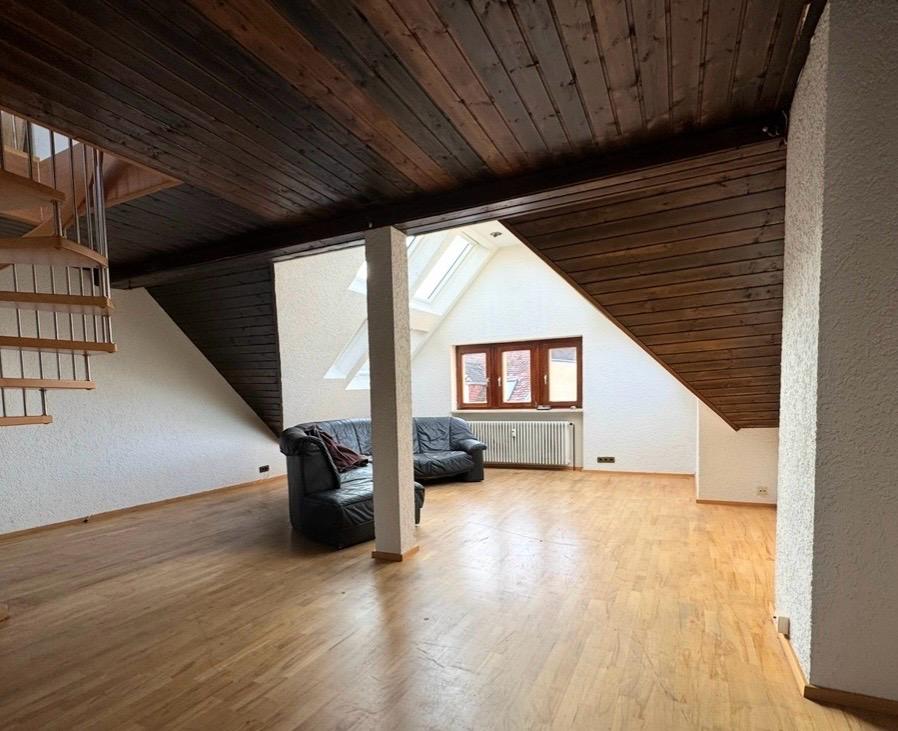 Dachgeschoss vor der Renovierung mit dunkel verkleideter Holzdecke und altem Parkett